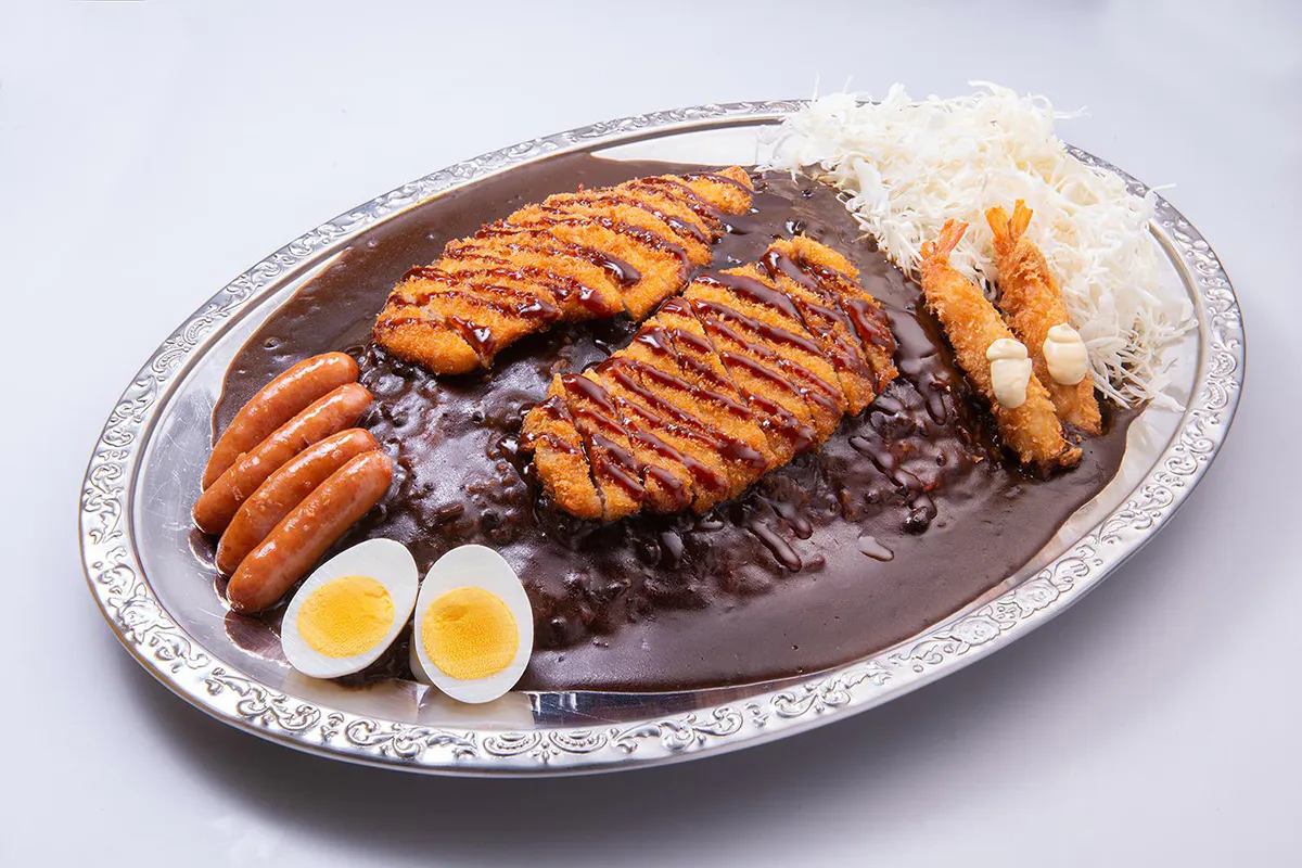 Large Japanese black curry platter with tonkatsu, fried shrimp, sausages, boiled egg, and cabbage at Go Go Curry, a Japanese Curry Restaurant in Gardena